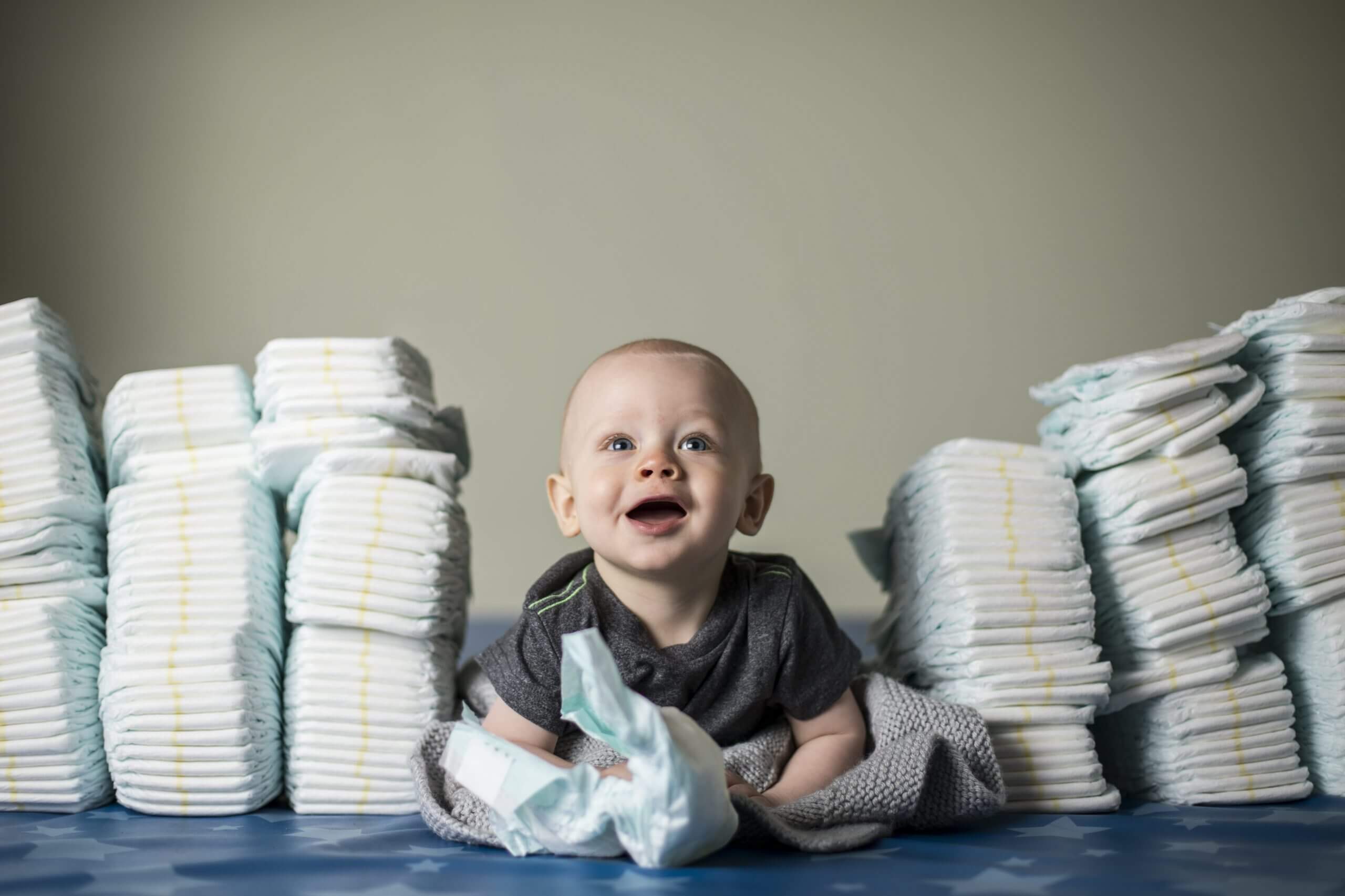 Baby surrounded by stacks of diapers representing how much of a financial responsibility a baby is.